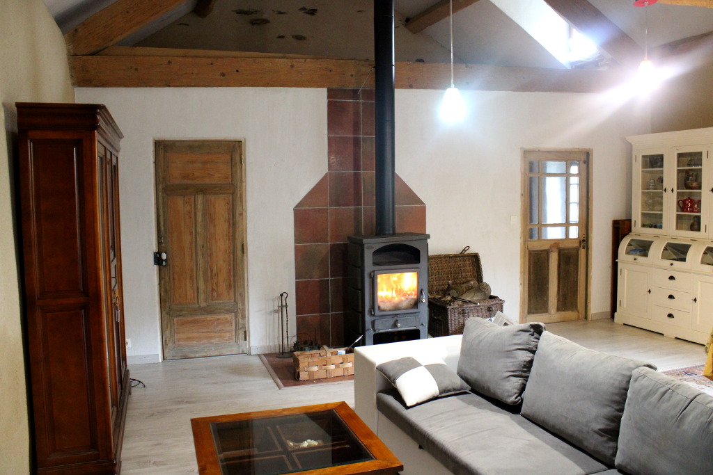 Vue sur le grand salon du gîte, avec canapé convertible, petite table basse et poêle à bois