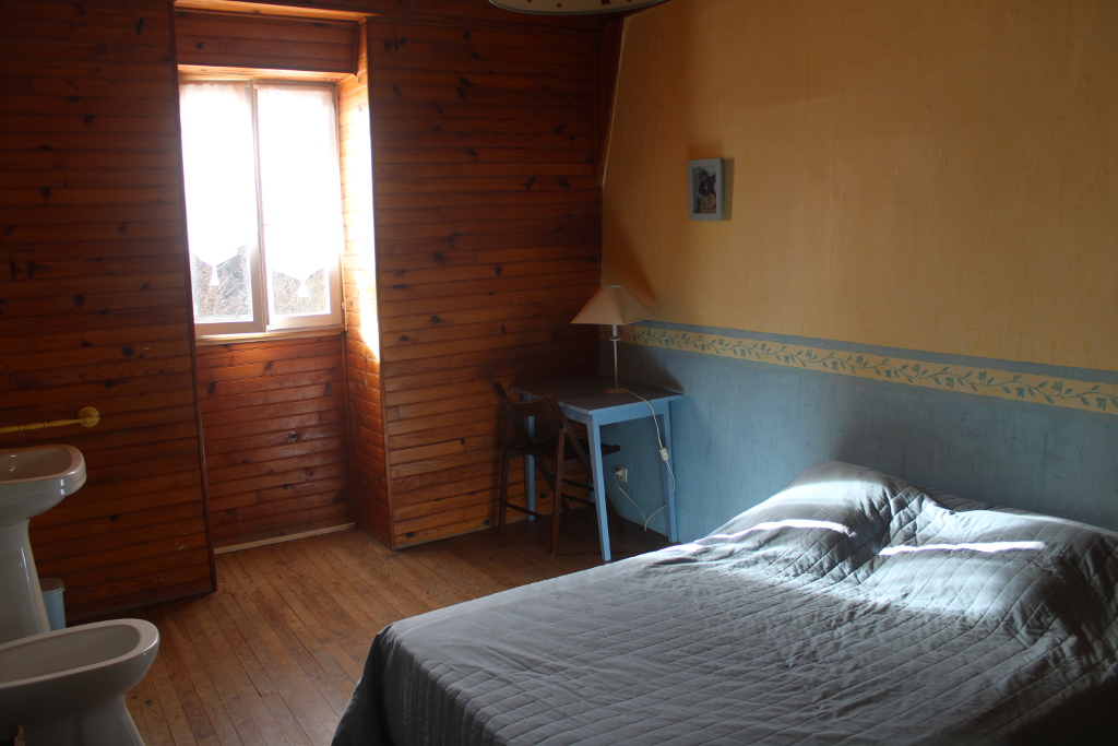 Vue sur la chambre rustique bleue : un lit double, une armoire (non visible), un lavabo, un bidet, une fenêtre lumineuse donnant sur le Viaur